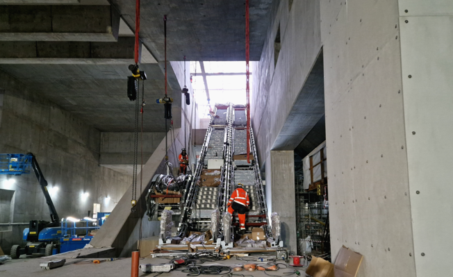 Bild på stationsutrymmet. Två rulltrappor är monterade och en till håller på att monteras.